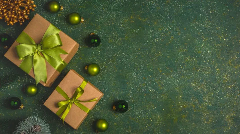 Two kraft-paper gift boxes with green bows and green baubles on a dark green background